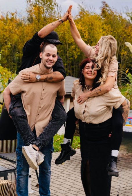 Zwei Paare stehen in einem Park und geben sich gegenseitig ein High-Five.