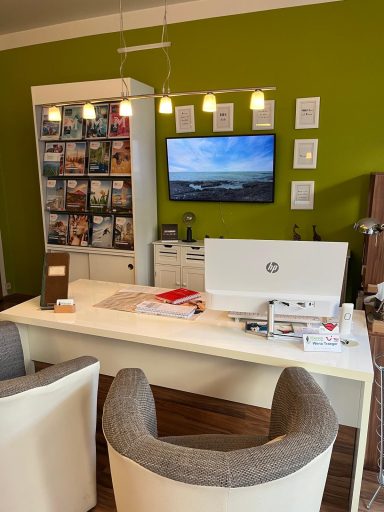 Moderne Büroecke mit Schreibtisch, Computer, Fernseher und Zeitschriftenregal.