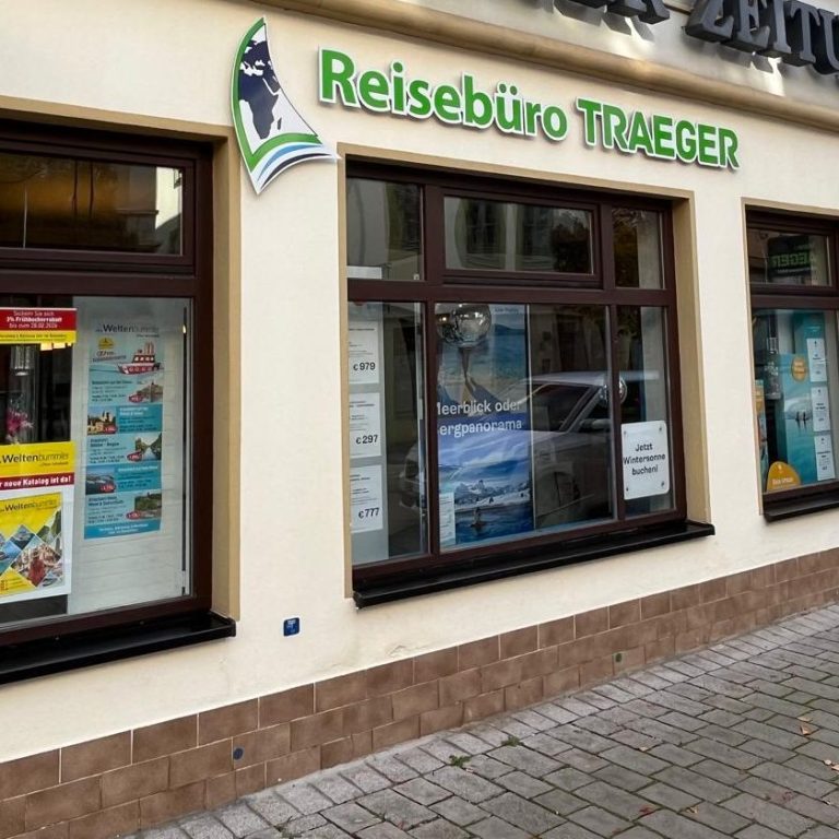 Schaufenster eines Reisebüros mit bunten Plakaten und dem Namen "Reisebüro Traeger".