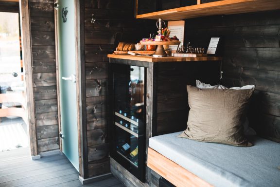 Gemütliche Innenansicht eines modernen, kleinen Holzhauses mit Sitzgelegenheit und Regal.