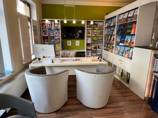 Moderne Empfangsbereich mit weißen Sesseln und Regalen voller Zeitschriften.