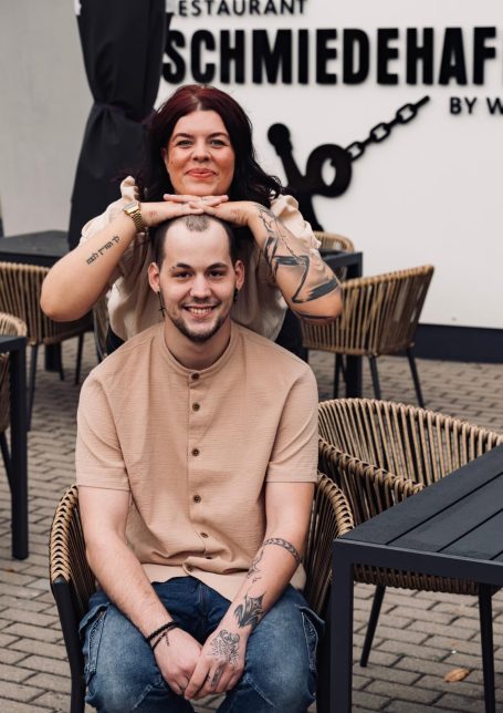 Frisörin stylt Haar eines Mannes in einem modernen Café mit Stühlen und Tischen.