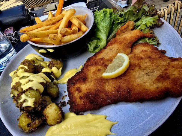 Brotet Fischfilet mit Zitrone, Pommes und buntem Salat mit Dressing.