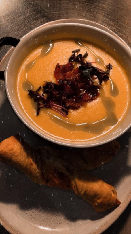 Kürbiscremesuppe mit Speckstückchen und knusprigem Blätterteiggebäck.